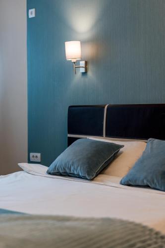 a bed with two pillows and a light on the wall at French House in Belgrade