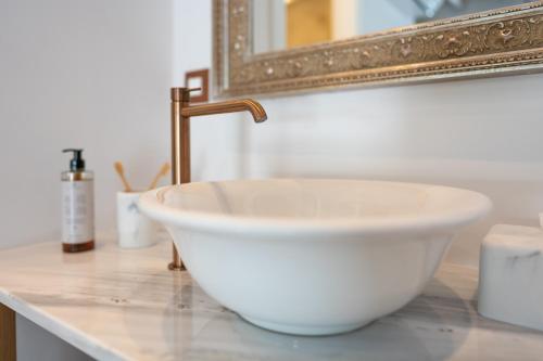 a white bowl sink on a counter with a mirror at Nisomar Suites in Symi