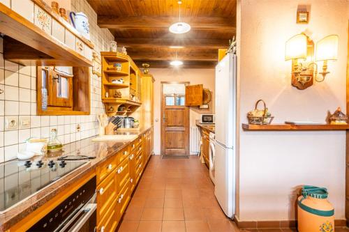 a kitchen with wooden cabinets and a white refrigerator at Mountain Lodge Can Campaner in Escaldes-Engordany