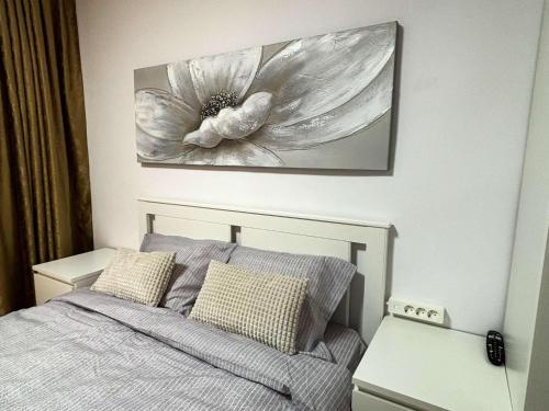 a bedroom with a bed with a flower painting on the wall at One Room Apartment Ptm 3 in Bucharest