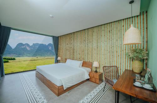 a bedroom with a bed and a desk and a window at Tu Lan Lodge in An Thọ Thôn