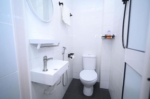 a white bathroom with a toilet and a sink at Swing & Pillows - Times Square, Bukit Bintang in Kuala Lumpur