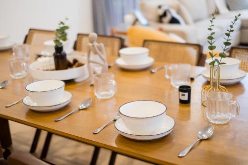 a wooden table with white dishes and spoons on it at Bungalow Putrajaya 15pax w Private Pool Gathering in Putrajaya