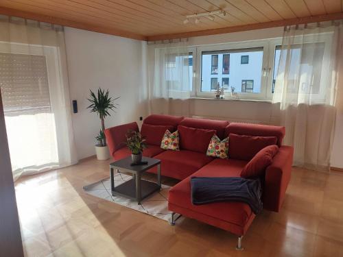 a living room with a red couch and a table at Ferienwohnung Unterm Tierstein in Bad Ditzenbach