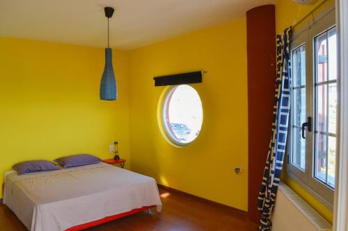 a yellow bedroom with a bed and a window at The Grand Beach House in Karistos