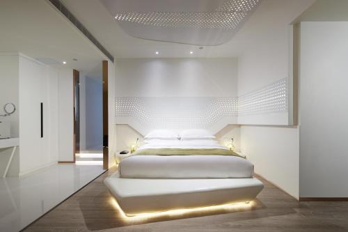 a white bedroom with a bed with lights on it at m58 Sky Sunset Hotel in Chongqing