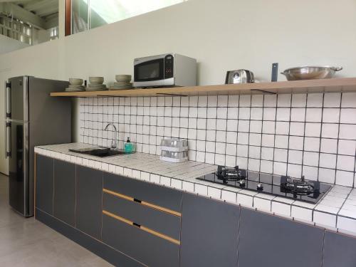 a kitchen with a sink and a microwave on a counter at HŌM Coliving Bali in Kerobokan