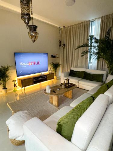 a living room with a white couch and a television at Arabian-Inspired 1BR - Polo Residence Near Burj in Dubai