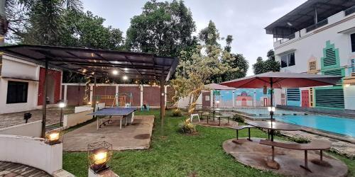 a patio with tables and umbrellas next to a pool at Villa Zam Zam Puncak in Puncak