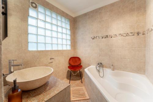 La salle de bains est pourvue d'une baignoire et d'un fauteuil rouge. dans l'établissement Au Coeur D'avignon, à Avignon
