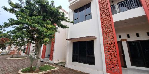 a white building with a tree next to a door at Villa Zam Zam Puncak in Puncak