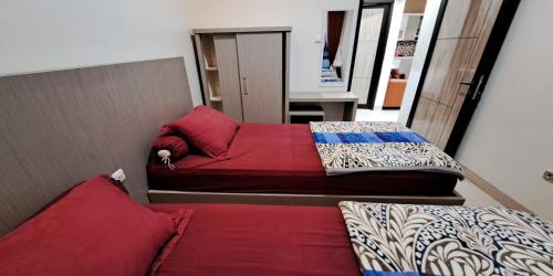 two beds in a small room with red pillows at Villa Zam Zam Puncak in Puncak