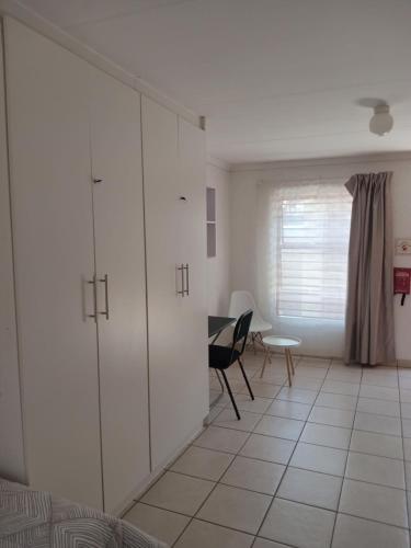 a living room with white cabinets and a table at Baksman's Retreat in Soweto