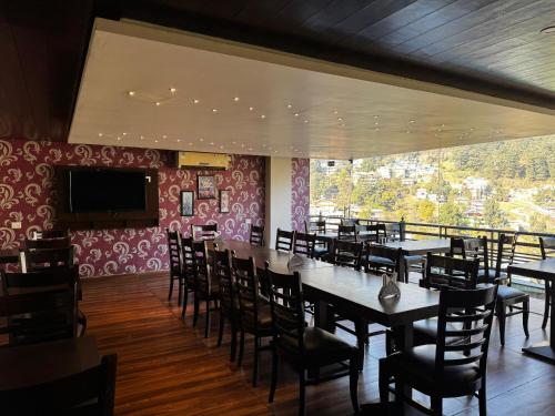a dining room with tables and chairs and a television at #The Vaikunth# Mcleodganj# Dhauladhaar View# Big free Parking# Ac rooms Centrally#Elevator#Soundproof rooms# in Dharmsala