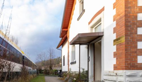 a side view of a white building with a train at homie stay Süßenmühle - Apartments am Bodensee in Sipplingen