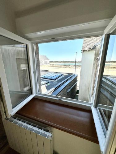 une fenêtre avec vue sur un toit dans l'établissement Maison de pêcheur atypique Les pieds dans l’eau, à Ploemeur