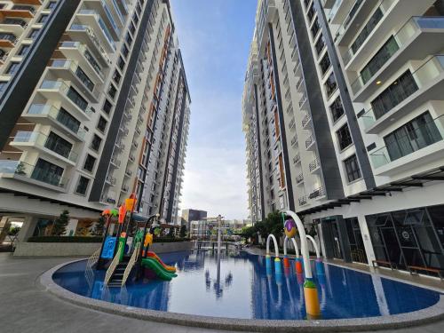 a pool with a playground in the middle of two tall buildings at K Avenue Kota Kinabalu by Merveille - Sabah in Donggongon