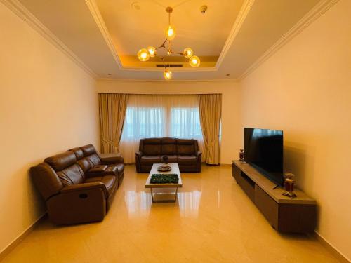 a living room with leather furniture and a flat screen tv at Al Hamra Residence in Ras al Khaimah