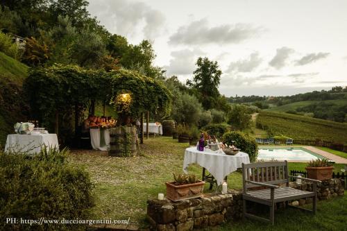 a group of people sitting at tables in a garden at Agriturismo & Winery Il Bacio in Tavarnelle in Val di Pesa