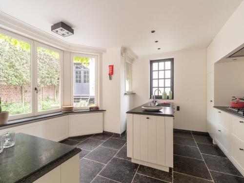 a kitchen with white cabinets and black tile floors at Huis Dries in Borgloon
