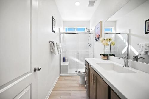 a white bathroom with a sink and a shower at Views, Gameroom, Saltwater Pool & Hot tub, Firepit by MariamsBnb in Desert Hot Springs