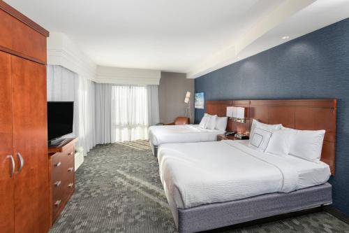 a hotel room with two beds and a flat screen tv at Courtyard by Marriott San Diego Oceanside in Oceanside