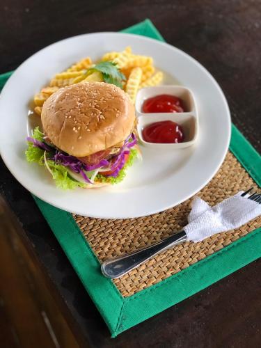 a plate of food with a sandwich and waffle fries at Doni House & Villas in Ubud