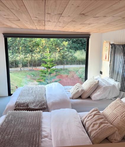 two beds in a room with a large window at Tiny Escape Charlotte in Pak Chong