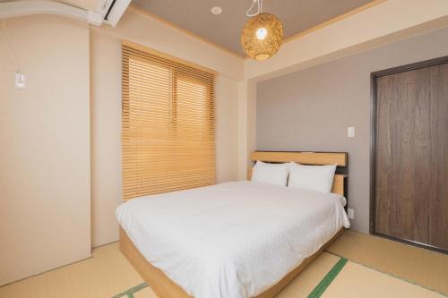 a bedroom with a white bed and a window at Miro Fusimiinari Tei North in Kyoto