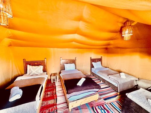 a room with three beds in a tent at Eco Merzouga luxury camp in Merzouga