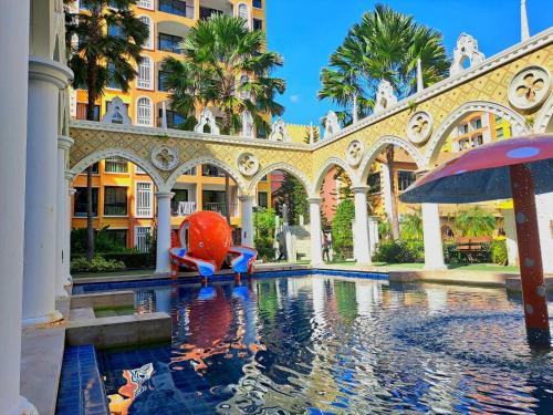 a swimming pool in a building with an umbrella at Venetian Signature Pattaya by รมิตา in Jomtien Beach