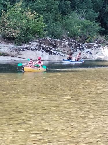three children are riding in kayaks on a river at Mado in Verfeuil