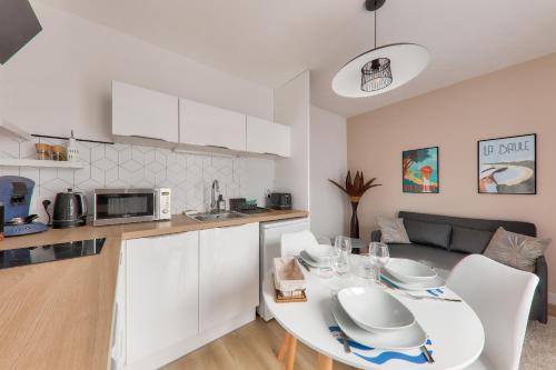 une cuisine et un salon avec une table et des chaises blanches dans l'établissement Maison pour 4 - proche plages et commerces, à La Baule