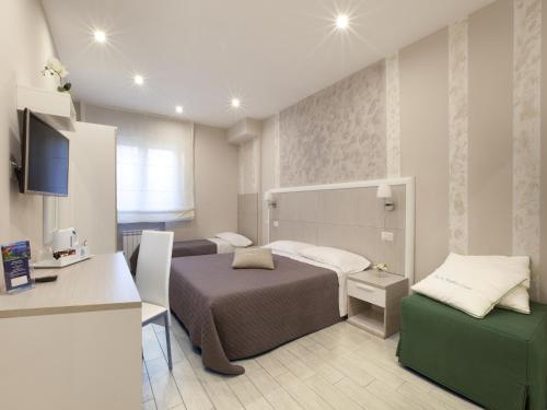 ソレントにあるLe Quattro Piazzeのベッドとデスクが備わる小さなホテルルームです。