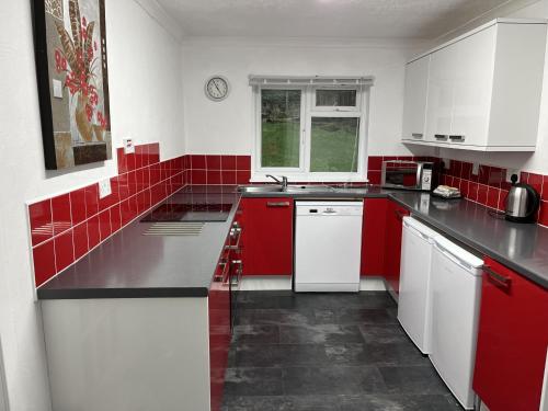 a red and white kitchen with white cabinets and red tiles at The Lodge in Lochgilphead