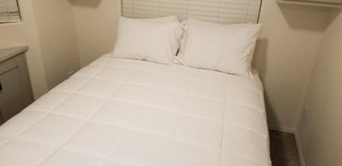 a bed with white sheets and pillows in a room at 038 Dine & Unwind Tiny Home near Grand Canyon South Rim in Valle