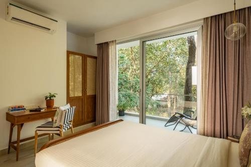 a bedroom with a bed and a desk and a window at La Olalian 2 & 3 BHK Designer Villas Near Anjuna Beach with Private Pool & Sun Deck & Garden in Anjuna