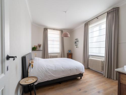 a bedroom with a bed and a table and two windows at Huis Dries in Borgloon