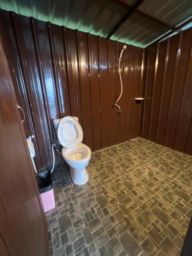 a bathroom with a toilet in a room with wooden walls at Tiger home stay Phayam in Ko Phayam