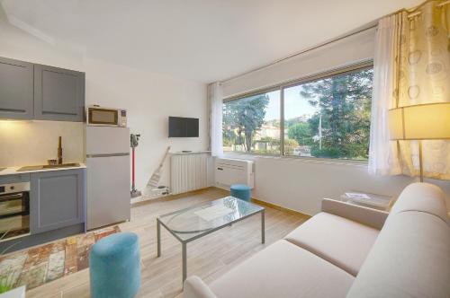 un salon avec un canapé blanc et une table en verre dans l'établissement Le Ray - Parking-2min Mer - VCA, à Cannes