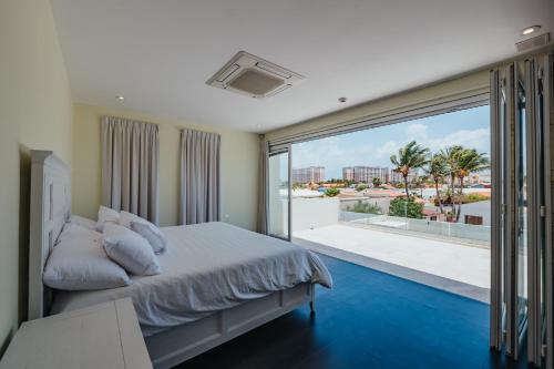 a bedroom with a bed and a large window at LUX 2BR Pool 5mins Beach Villa Ocean by Bocobay in Palm-Eagle Beach