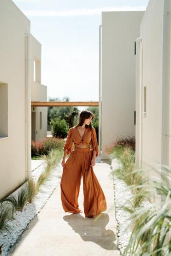 a woman in a orange dress walking down a sidewalk at Magnolia Villas Potos Thassos in Potos