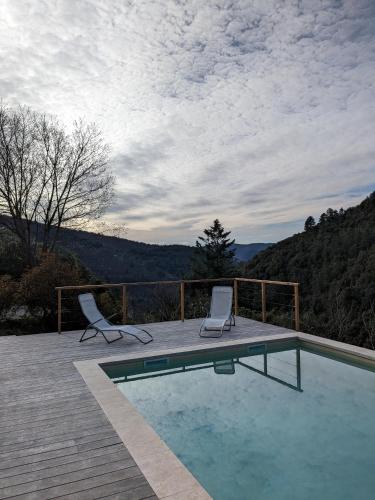 - une piscine avec deux chaises assises sur une terrasse dans l'établissement Mas du ciel en Cévennes, à Arphy
