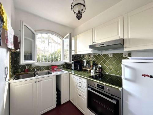 une cuisine avec des armoires blanches et un réfrigérateur blanc dans l'établissement HYEGRASSE Villa pour 6 personnes à 100 mètres de la plage situé sur le Port d'Hyères, à Hyères