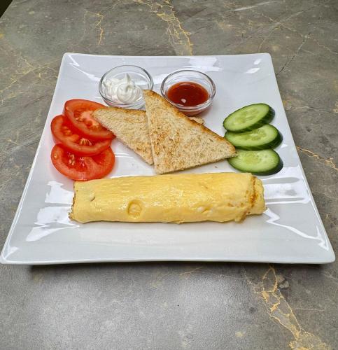 a white plate with an omelet and vegetables on it at Lion Hotel in Astana