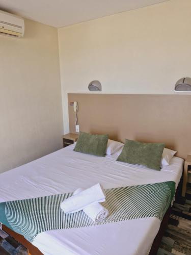 a bedroom with a white bed with two green pillows at Hotel de la Plage - Barcares in Le Barcarès