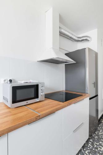une cuisine blanche avec un four micro-ondes sur un comptoir dans l'établissement Appartement Paisible proche parc des princes - 4P - FLAT-GUEST, à Boulogne-Billancourt