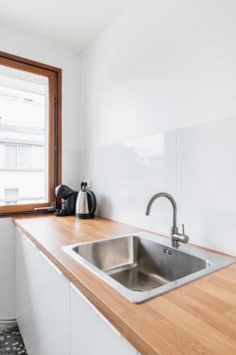un comptoir de cuisine avec un évier et une fenêtre dans l'établissement Appartement Paisible proche parc des princes - 4P - FLAT-GUEST, à Boulogne-Billancourt