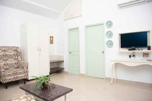 a living room with a tv and a chair and a table at Casa Flore- 1bhk studio apt in Bardez