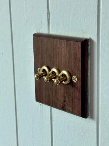 a wooden switch with three gold knobs on it at Tiny Escape Charlotte in Pak Chong